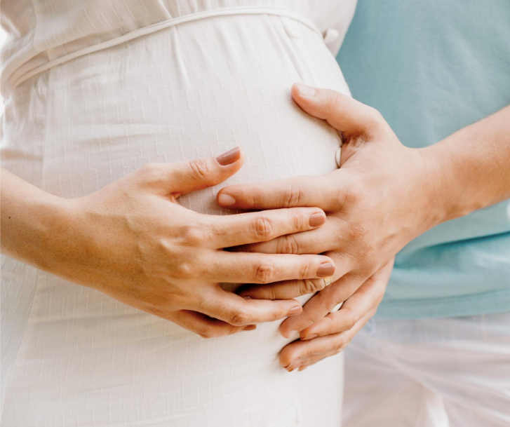Gravid person håller händerna om magen